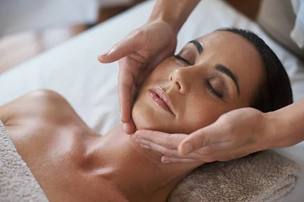 Massage Kobido sur visage, lumière tamisée, ambiance bien-être, mains expertes